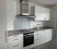 Modern kitchen with white cabinets, granite countertop, stainless steel oven, sink, and range hood.
