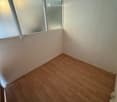 Empty room with light wooden flooring and white walls, featuring large windows with frosted glass panels.