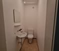 Small bathroom with a toilet, sink, mirror, and a single light fixture on the ceiling.