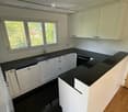 Modern kitchen with white cabinets, black countertops, and a stainless steel sink and faucet.