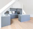 Modern kitchen with grey cabinets, white countertops, and wooden flooring. Features a sink, faucet, and built-in oven.