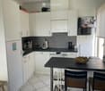 Modern kitchen with white cabinets, stainless steel appliances, and a black island with a fruit bowl and chairs.