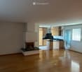 Open-plan living and kitchen area with wooden flooring, fireplace, and modern kitchen cabinets.