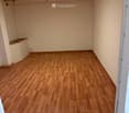 Empty room with wooden flooring and white walls, featuring a small built-in shelf on one wall and a ceiling light fixture.