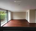 Empty room with wooden flooring, large windows, and neutral-colored walls.