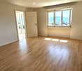 Empty room with wooden flooring, large windows, and a door leading to a balcony.