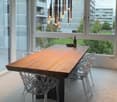 A dining room with a large wooden dining table, four transparent chairs on each side, and a large glass door leading to a view outside