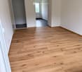 Empty hallway with light wooden flooring, white walls, and recessed lighting. Doors lead to adjacent rooms.