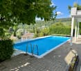 Outdoor area with a swimming pool, surrounded by greenery and offering a scenic view of the countryside.