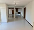 Empty hallway with white walls, polished floor, and recessed lighting. Features a large open closet on the left and a doorway leading to another room with a fireplace and bathtub visible in the background.