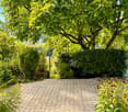 Well-maintained garden with a swimming pool, lush greenery, and a brick patio.