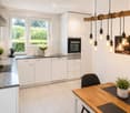 Modern kitchen with white cabinets, granite countertops, stainless steel appliances, and a wooden dining table with a potted plant.