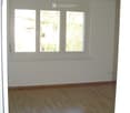 Empty room with wooden flooring and large windows, no furniture or equipment.