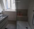 Modern bathroom with a sleek sink, glass shower enclosure, and large windows allowing natural light.