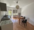 Open-plan kitchen and dining area with wooden flooring, modern appliances, and a dining table with chairs.