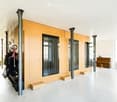 Modern, minimalist room with a large piano, a small stool, a tall storage unit with a bicycle, and large windows with curtains.