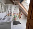 Bathroom with a white sink, mirror, shower curtain with butterfly design, and a small wooden shelf holding toiletries.