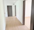 Empty hallway with light wooden flooring, white walls, and three doors leading to other rooms.