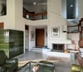 Modern living room with a fireplace, leather sofa, glass coffee table, bookshelf, and decorative items.