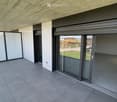 Modern balcony with large glass sliding doors, tiled floor, and a view of the surrounding landscape.