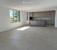 Empty kitchen with modern fitted cabinets, large windows, and tiled floor.