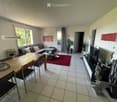 Bright living and dining area with a sofa, dining table, chairs, coffee table, TV, and decorative items.