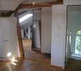 Bright, open attic space with wooden beams, wooden flooring, and large skylight windows. The room is empty, with no furniture or furnishings visible.