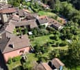 Aerial view of a residential area with multiple houses, tiled roofs, and surrounding greenery.