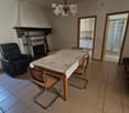 Living room with tiled floor, fireplace, sofa, dining table with chairs, and a view into the kitchen area.