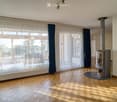 Living room with wooden flooring, large windows, and a modern fireplace.