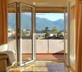 white couch, white pillow, open sliding glass doors, balcony, tiled floor, view of mountains