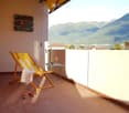 Balcony with a wooden chair, a small table, and a view of the mountains