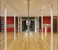 Open-plan space with wooden flooring, white columns, red cabinetry, and glass doors leading to another area.
