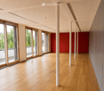 Empty hallway with wooden flooring, white walls, large sliding glass doors, and red storage units.