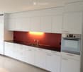 Modern kitchen with white cabinets, dark countertops, and built-in appliances including a sink and oven.