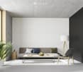 Spacious living room with concrete ceiling, white textured walls, large windows, gray sofa with colorful pillows, wooden coffee table, and a black accent chair. The room also features a potted plant, adding a touch of greenery.