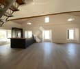 Open-plan space with wooden flooring, kitchen island, built-in oven, and cabinetry. Natural light from multiple windows and skylights.