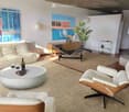 Modern living room with a white sofa, round coffee table, two wooden chairs, a bottle of wine, and two cups on the table. There are two paintings on the wall and a plant in the corner.