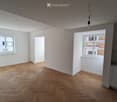 empty room, wooden parquet floor, white walls, two windows, kitchen area with sink