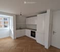 modern kitchen with white cabinets, wooden floor, window, sink, oven, and a lamp
