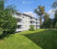 Apartment building with balconies, surrounded by trees and grass