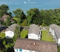 Aerial view of a residential complex with multiple buildings, green lawns, and a scenic lake view in the background.