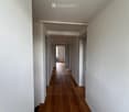 Empty hallway with wooden flooring, white walls, and several doors leading to other rooms.