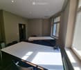 Bright, unfurnished room with large windows, a white table, a chair, and a screen on the table.