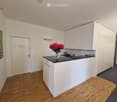 Modern kitchen with white cabinets, black countertop, and a vase of red flowers on the counter.