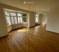 Empty room with hardwood floors, large windows, and radiators.