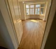 empty room, wooden floor, white walls, large windows, white door, radiator