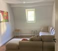 Living room with a beige sectional sofa, ottoman, side tables, a lamp, and a painting on the wall.