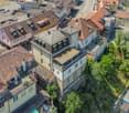 Aerial view of a residential area with multiple houses featuring red-tiled roofs, various architectural styles, and surrounding greenery.