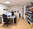 Modern office space with a desk, ergonomic chair, computer, keyboard, mouse, telephone, filing cabinet, potted plants, coffee maker, printer, picture frame, whiteboard, and a fan.